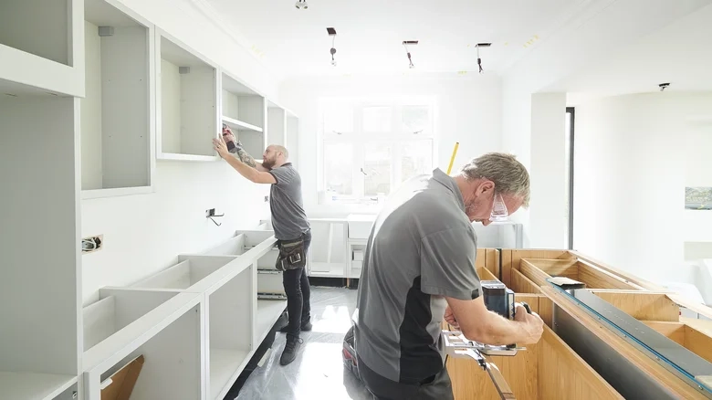 Two workers installing kitchen cabinets in a bright, modern space. -kitchen remodel bellevue wa