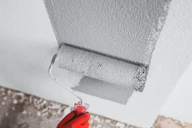 Close-up roller applies thick coat, emphasizing interior and exterior painting.